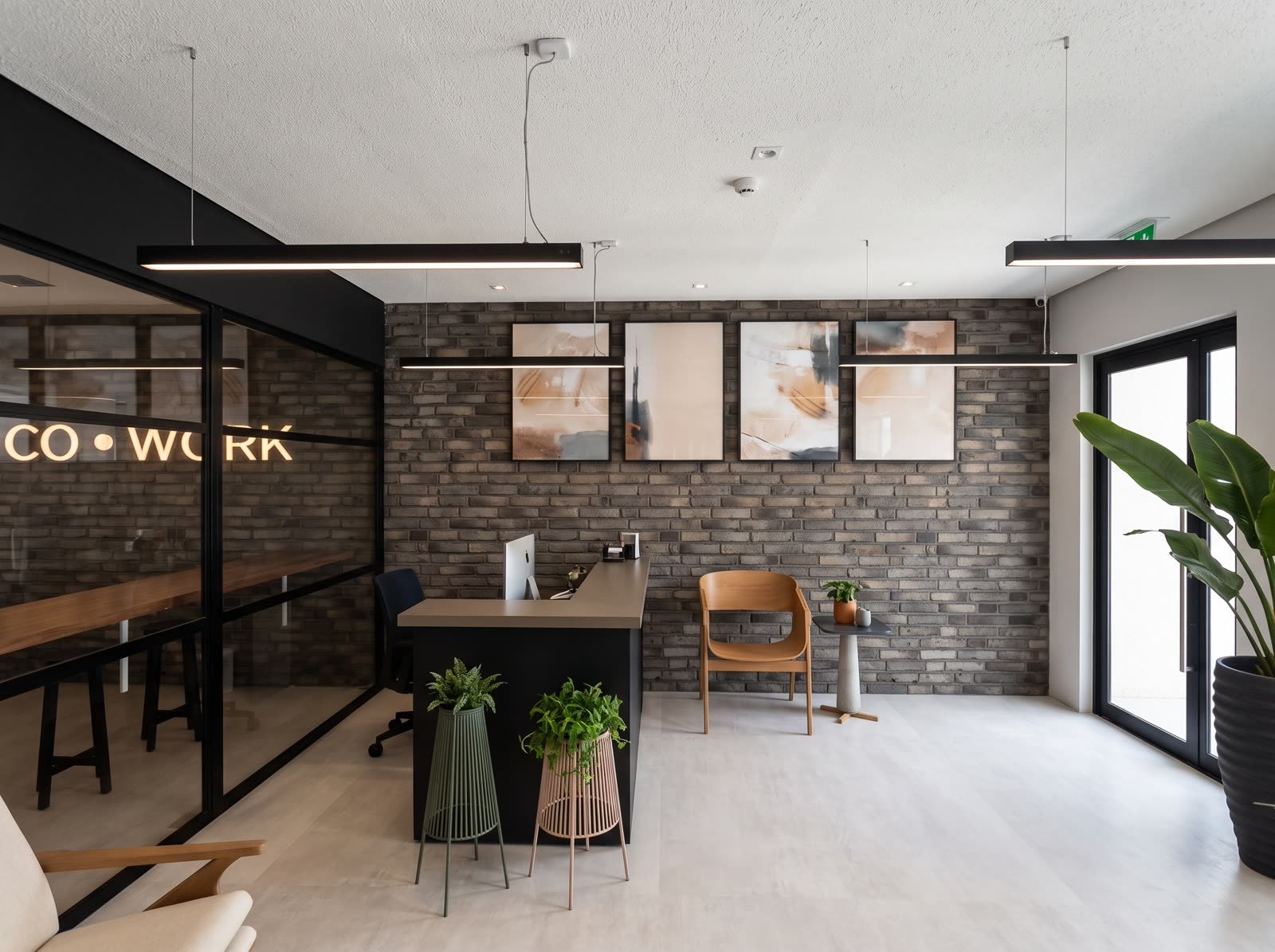 Espaço coworking com recepção e parede de tijolo